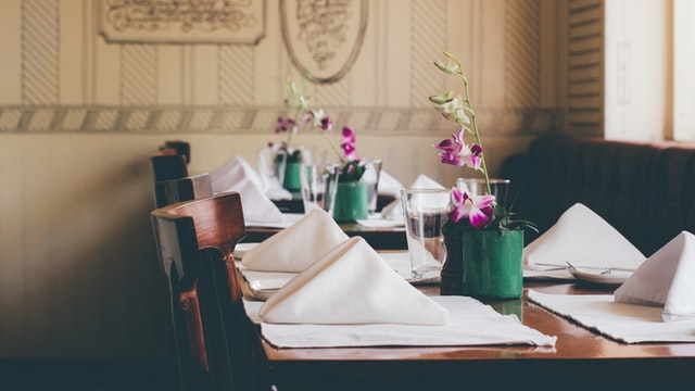 Jídelna v restauraci, nazdobené stoly, prostřeno s ubrousky a květinou